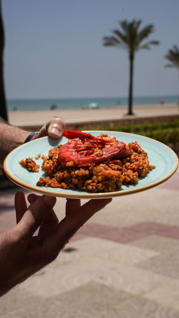 Plato de arroz con gamba roja en la terraza con vistas a la playa